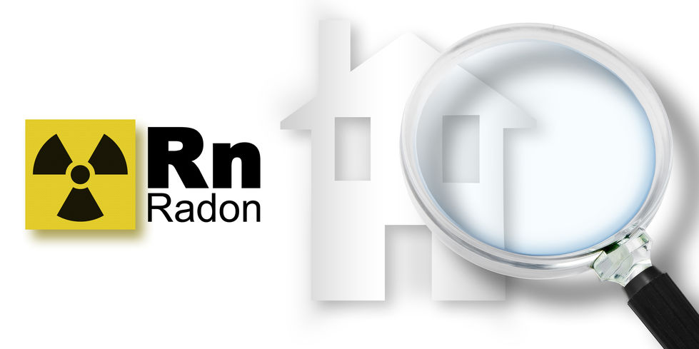 A home with the symbol for radon gas next to it. A magnifying glass is there to symbolize looking for radon gas.